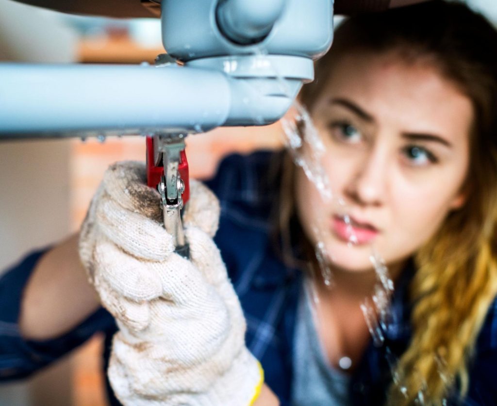 A woman is fixing the toilet sink.