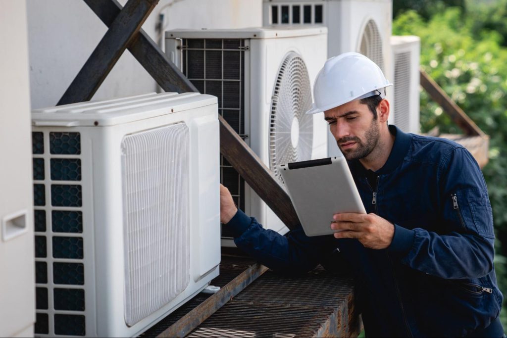 An HVAC technician inspects the air conditioning cooling system of a commercial building.