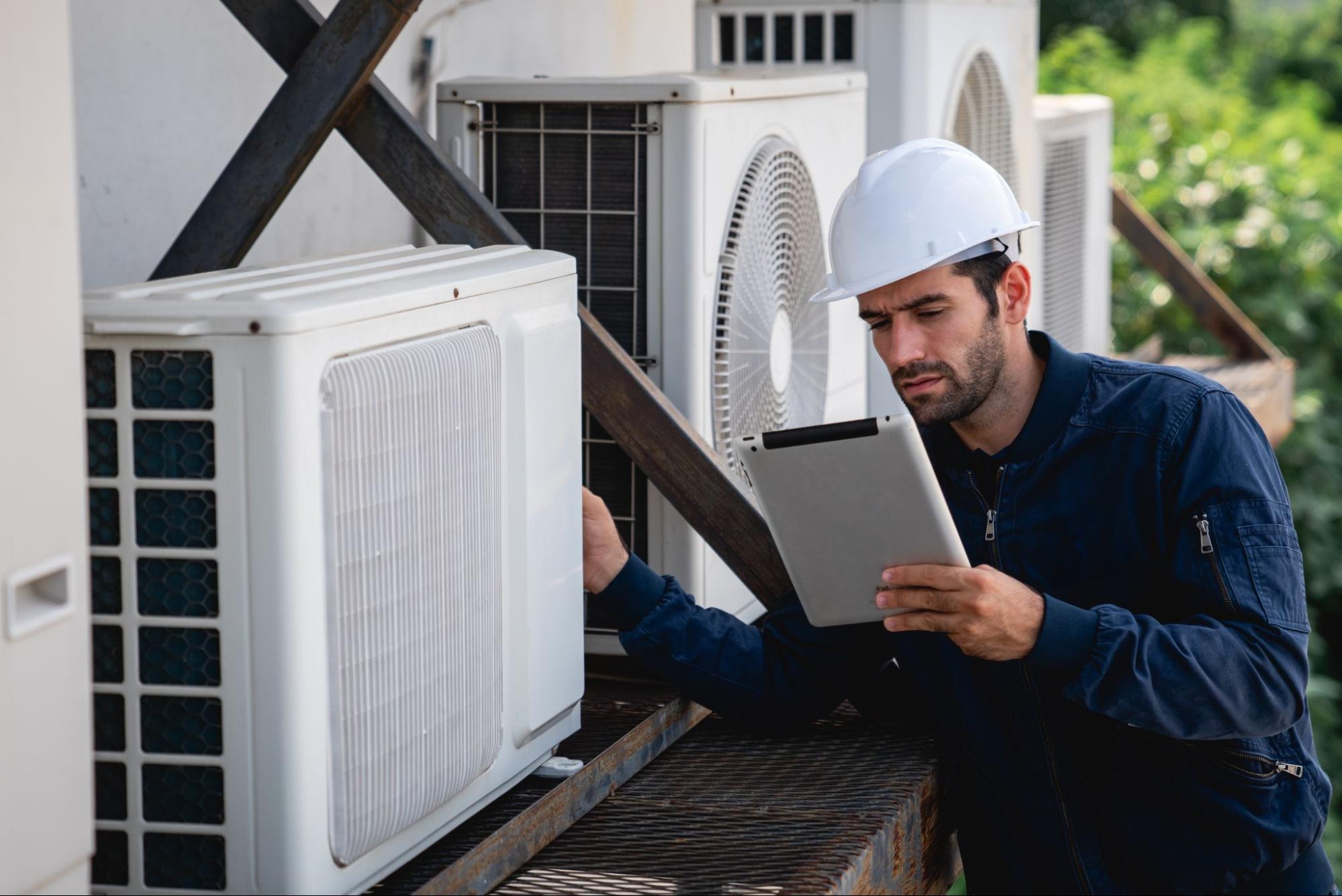 An HVAC technician inspects the air conditioning cooling system of a commercial building.