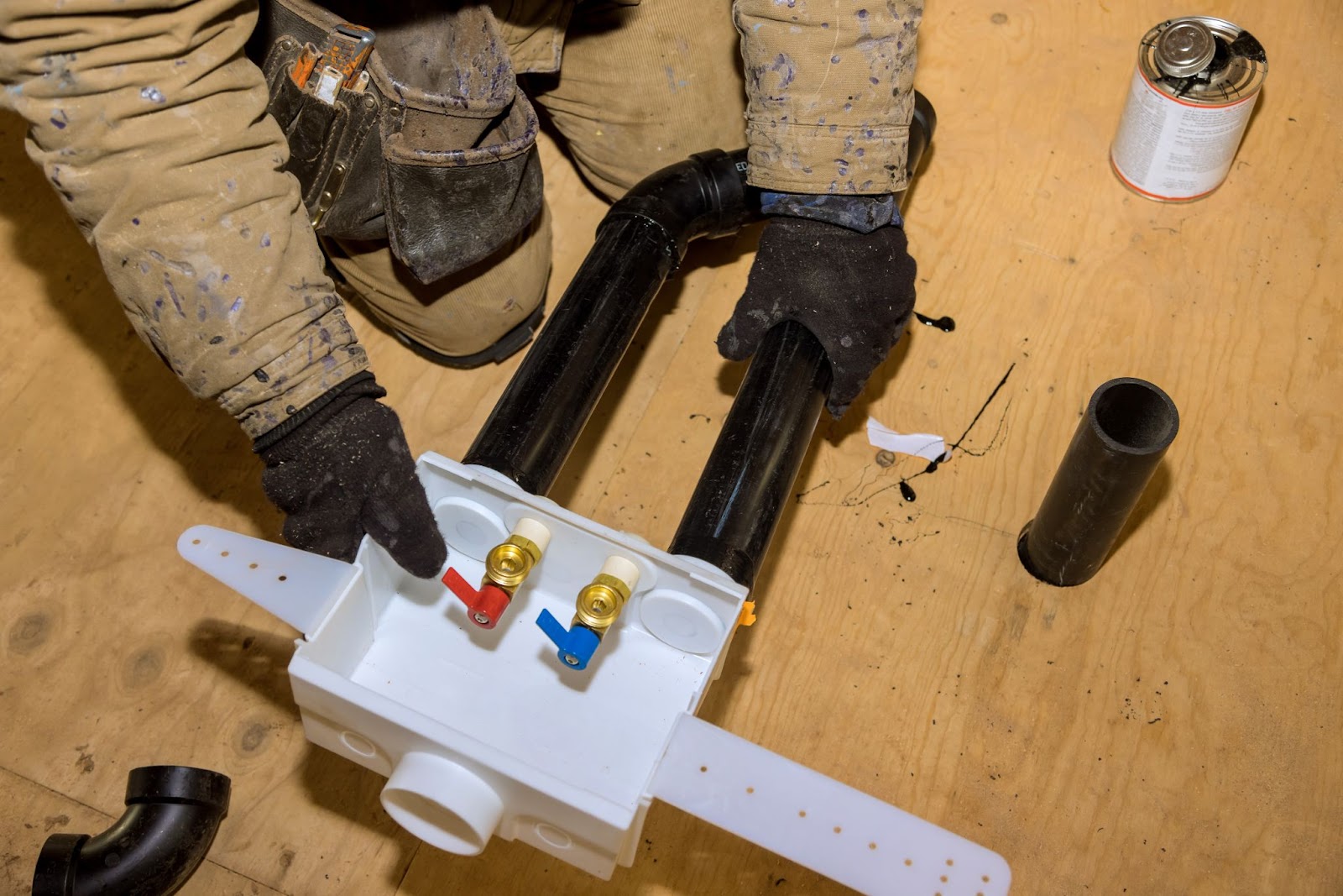 A plumber installing a laundry outlet box in a new home for washing machine water connections