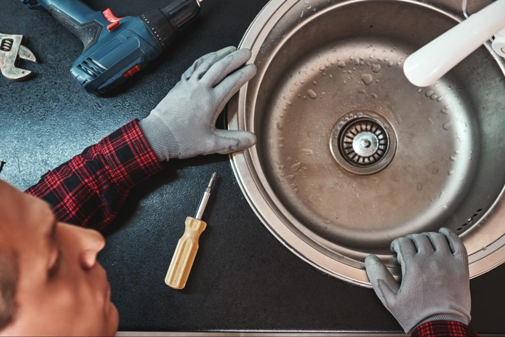 Overhead view of a plumber performing sink repair in a modern kitchen.