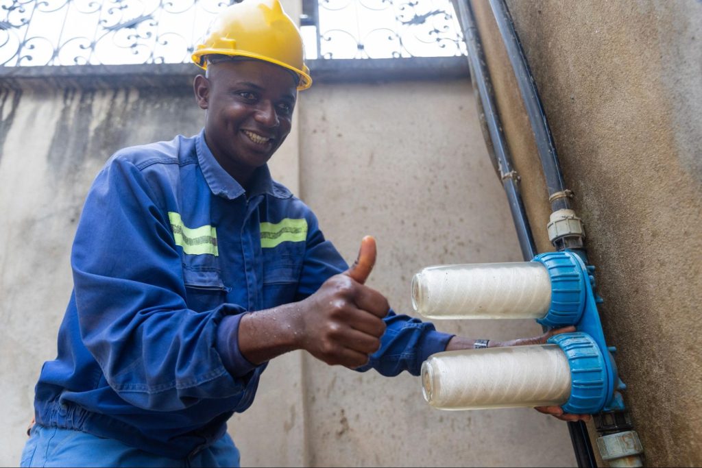 A plumber gives a thumbs up after replacing pre-filters in a water softener system.