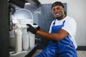 A plumber in uniform performing a water softener service.
