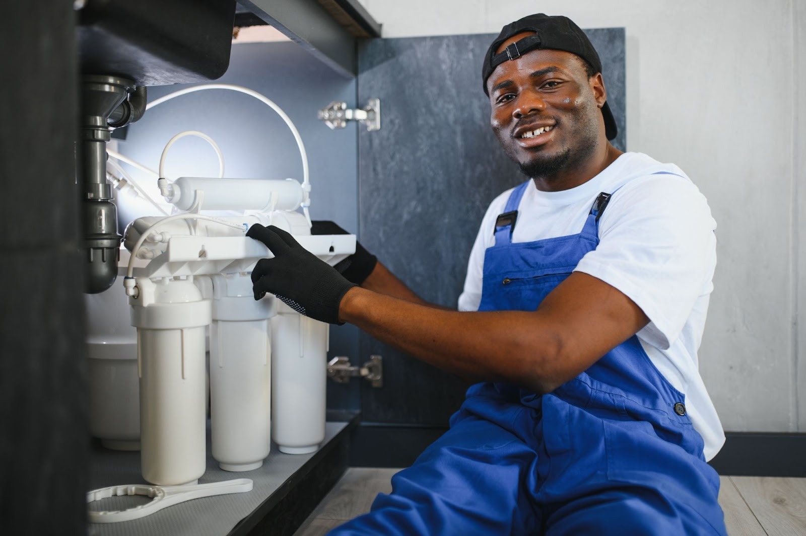 A plumber in uniform performing a water softener service.