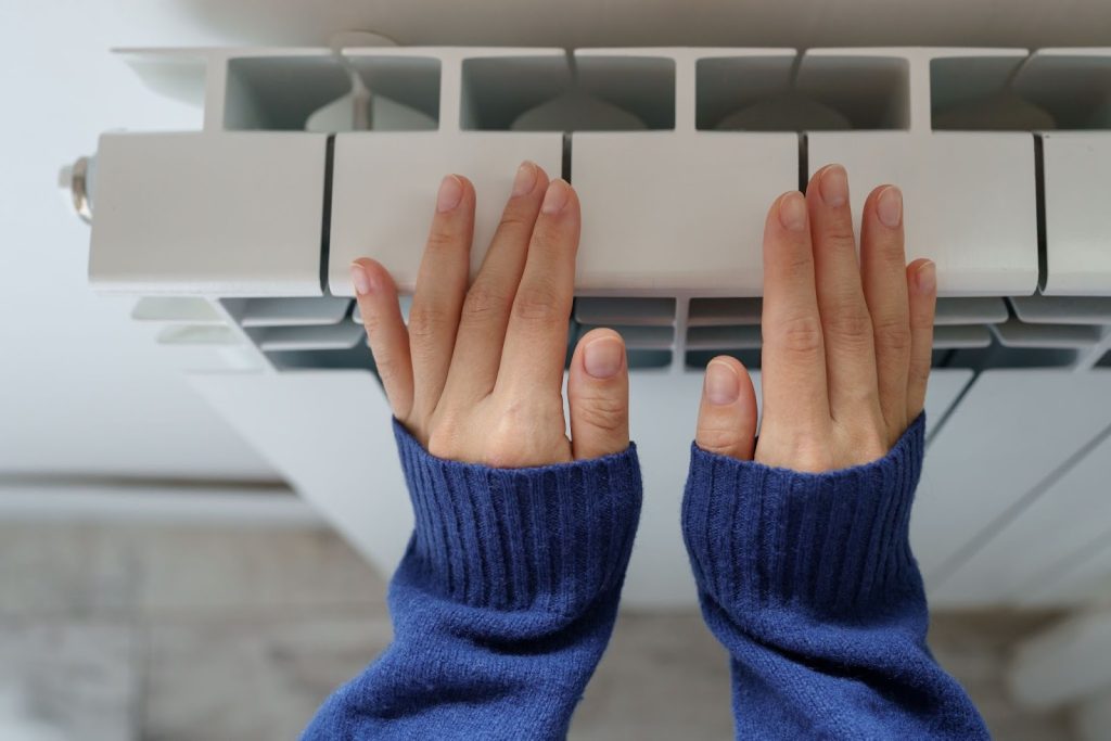 A close-up image of a woman’s hands against a furnace.