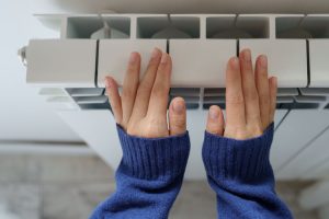 A close-up image of a woman’s hands against a furnace.