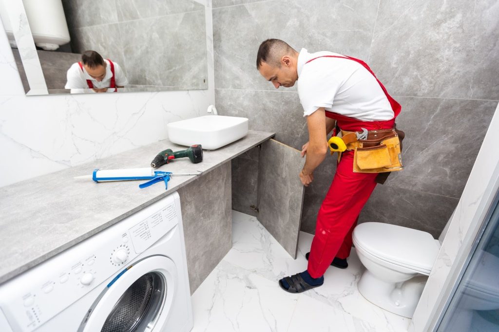 Plumbing repair service technician opening the cabinet beneath a sink