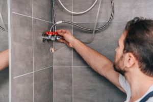 A male plumber repairing a tankless water heater in a residential bathroom