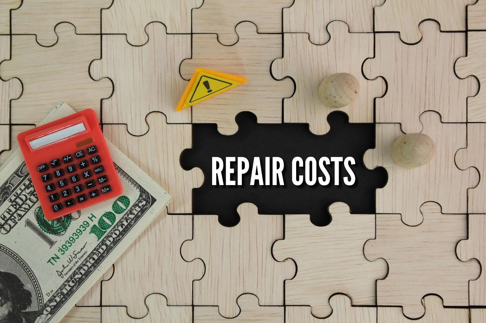 Wooden puzzle spelling “repair costs” beside a red calculator, paper money, and a small caution sign