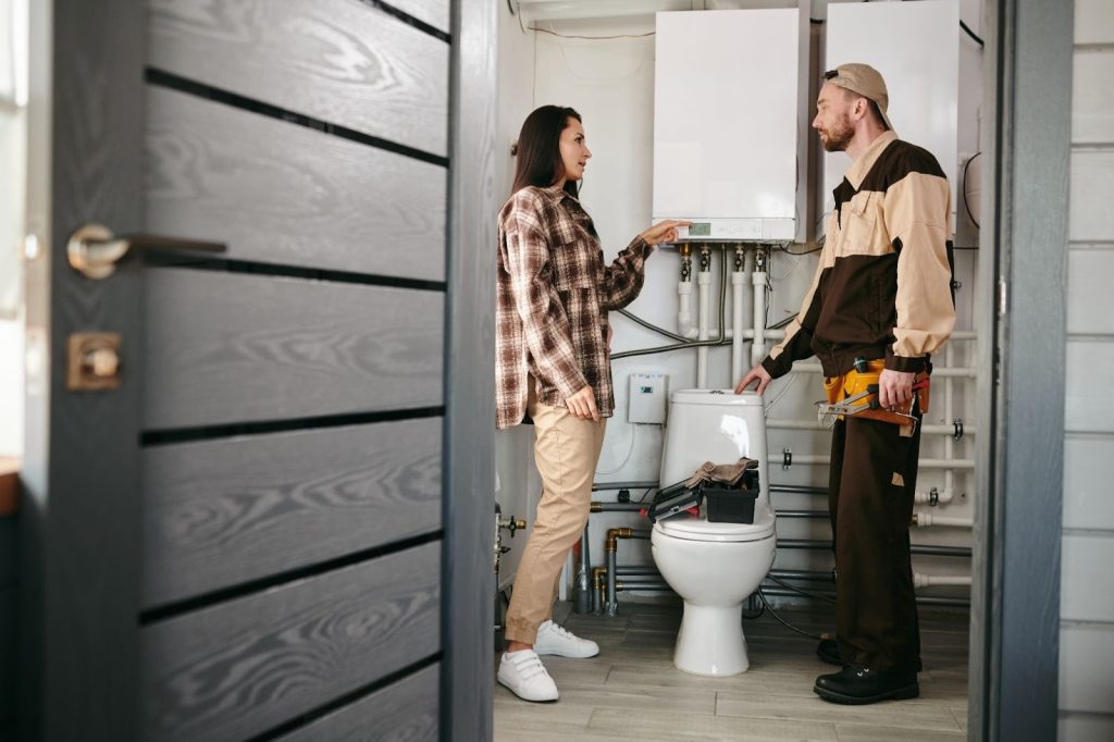 A local plumber explains a bathroom plumbing issue to a homeowner during an in-home inspection.